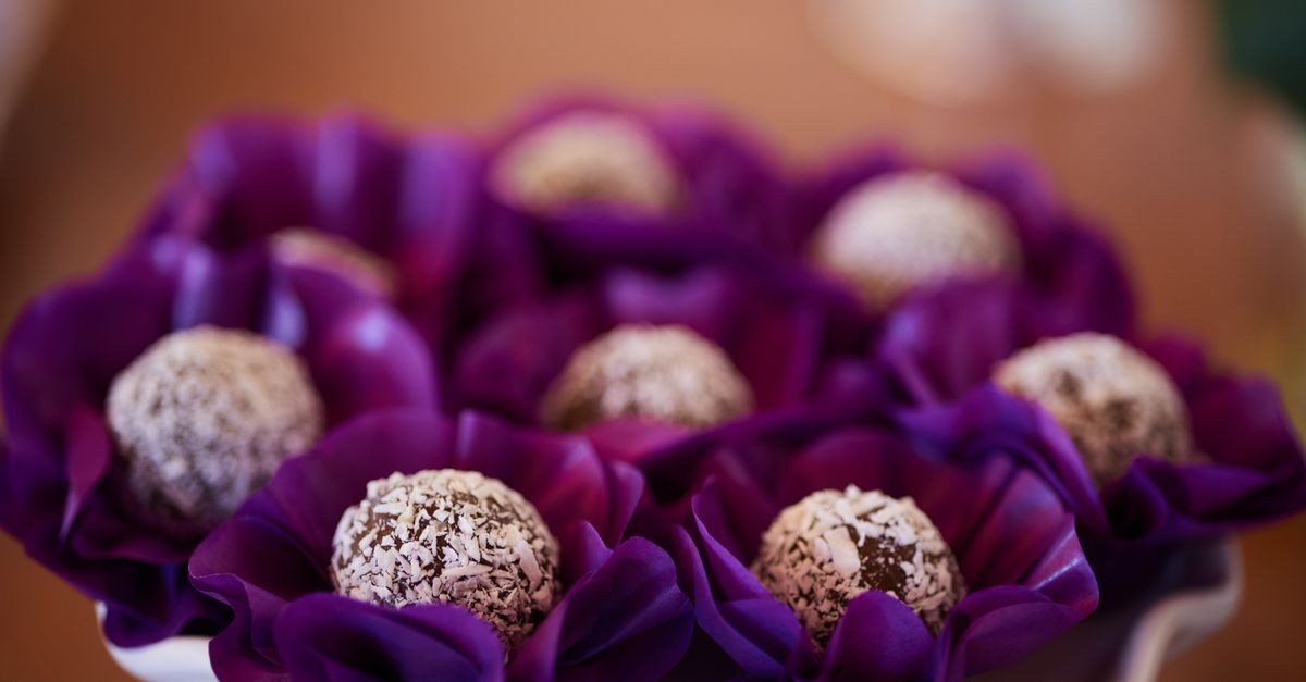 Delicious coconut truffles beautifully arranged in vibrant purple flower wrappers, perfect for parties.
